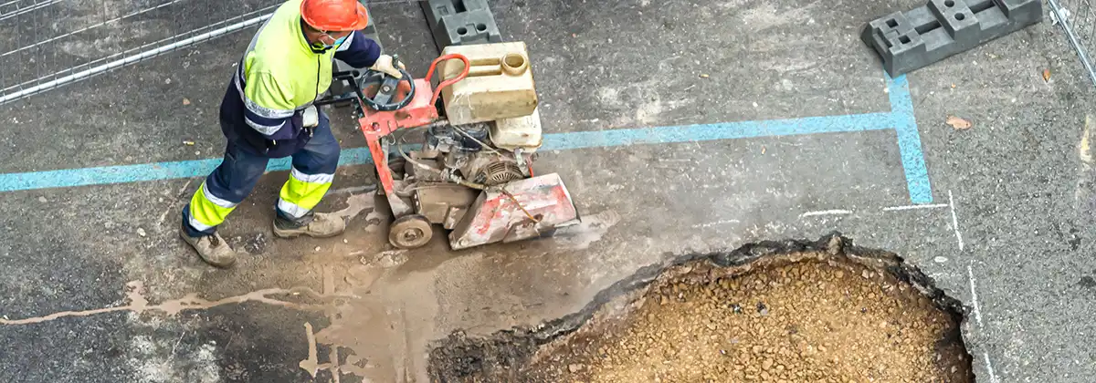 Bauarbeiter, der mit einer Schneidemaschine Asphalt von einer Straße schneidet